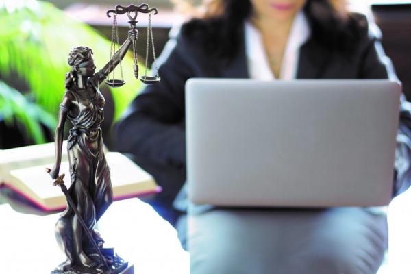 Woman working on her laptop with a statue of Lady Justice next to her